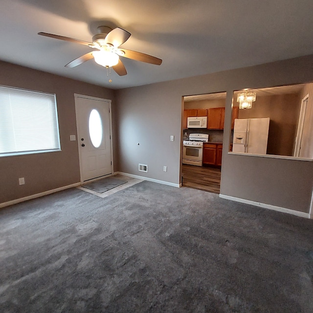 entrance foyer with ceiling fan with notable chandelier, dark carpet, visible vents, and baseboards