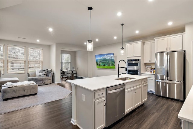 kitchen featuring sink, white cabinetry, pendant lighting, stainless steel appliances, and a kitchen island with sink