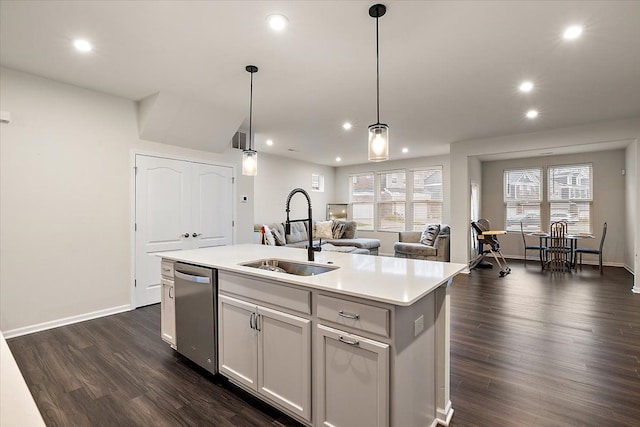 kitchen with sink, a kitchen island with sink, white cabinetry, decorative light fixtures, and stainless steel dishwasher