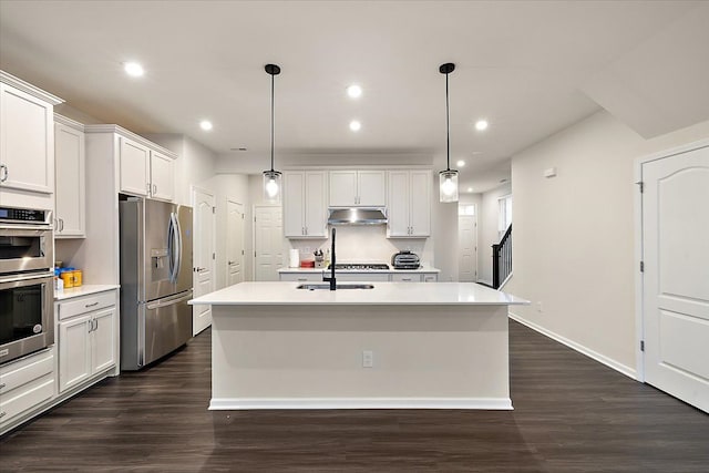 kitchen with dark hardwood / wood-style floors, an island with sink, white cabinets, hanging light fixtures, and stainless steel appliances