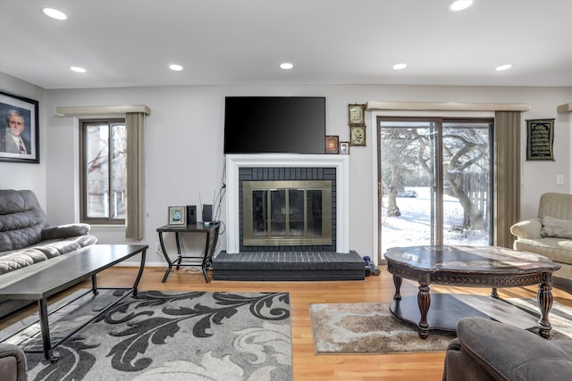 living room featuring a brick fireplace, hardwood / wood-style flooring, and a wealth of natural light