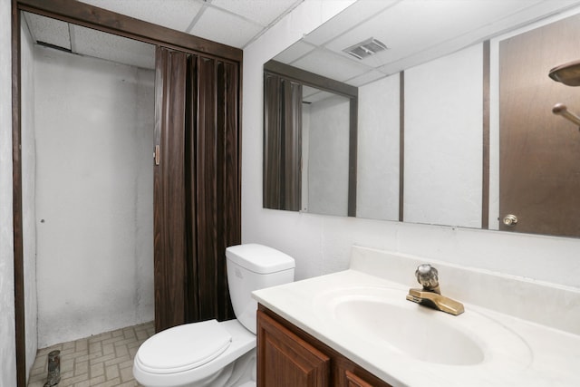 bathroom featuring vanity, toilet, and a drop ceiling