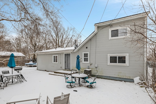 snow covered rear of property featuring cooling unit and a trampoline