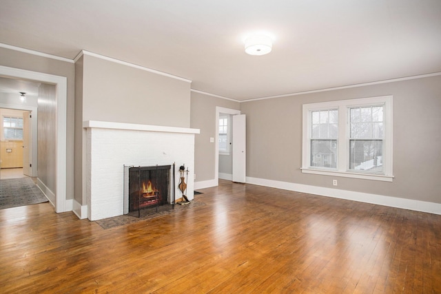 unfurnished living room featuring hardwood / wood-style flooring, ornamental molding, and a brick fireplace