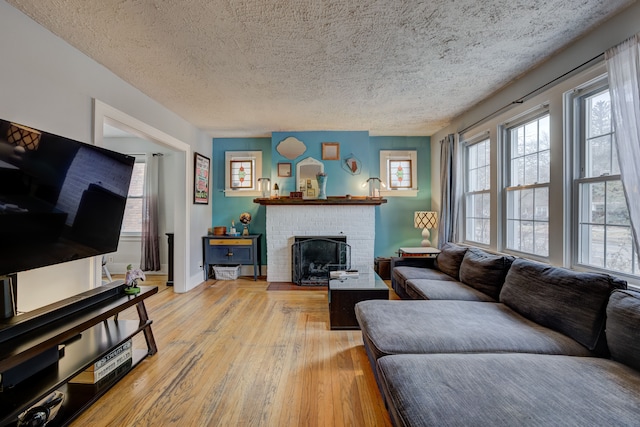 living area featuring light wood-type flooring, a healthy amount of sunlight, a fireplace, and a textured ceiling