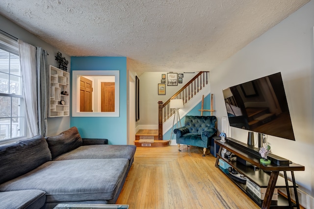 living room featuring a textured ceiling, stairway, and wood finished floors