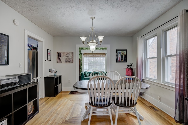 dining space with visible vents, baseboards, a chandelier, and a textured ceiling