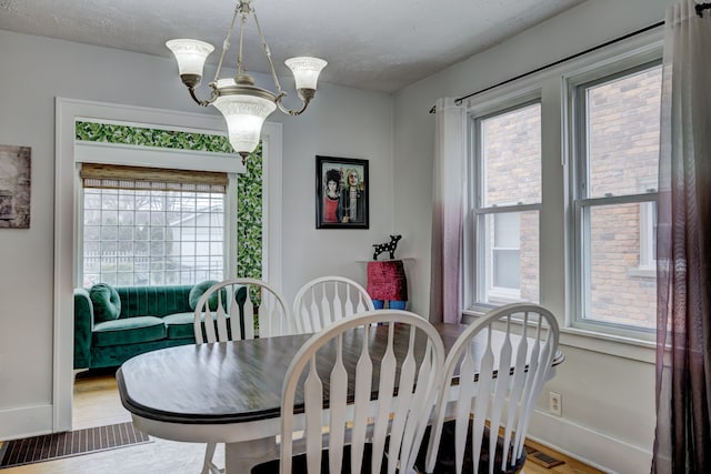 dining room featuring a chandelier, a healthy amount of sunlight, visible vents, and a textured ceiling