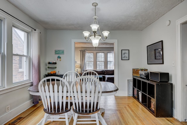 dining area featuring an inviting chandelier, baseboards, visible vents, and a wealth of natural light