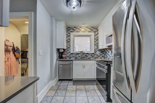 kitchen with stainless steel appliances, backsplash, dark countertops, and a sink