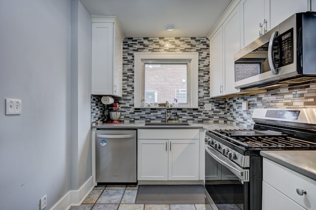 kitchen featuring white cabinets, decorative backsplash, stainless steel appliances, light countertops, and a sink