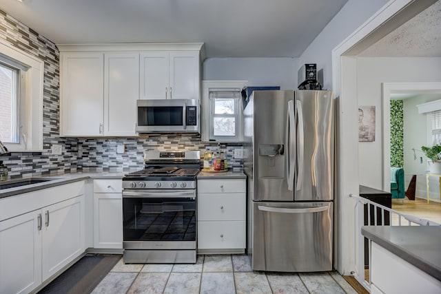 kitchen with appliances with stainless steel finishes, white cabinetry, a sink, and decorative backsplash