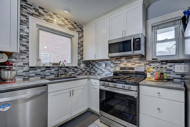 kitchen with stainless steel appliances, white cabinets, a sink, and decorative backsplash