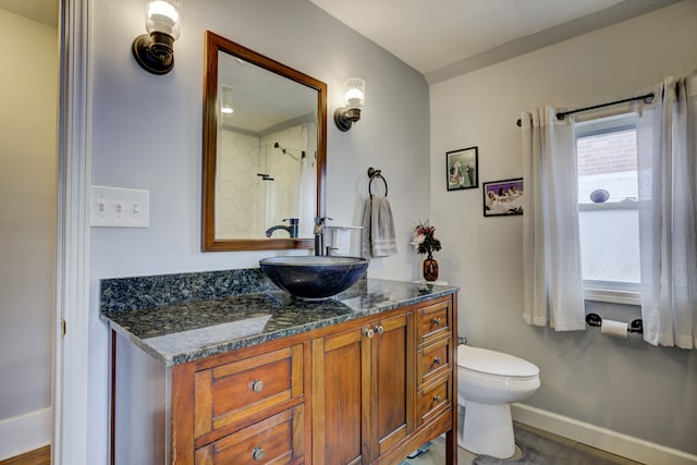 bathroom with toilet, vanity, a wealth of natural light, and baseboards