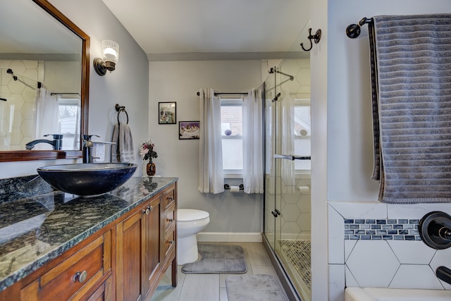 bathroom with toilet, a stall shower, vanity, and baseboards