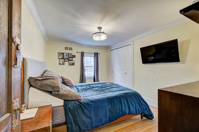 bedroom featuring crown molding, a closet, visible vents, wood finished floors, and baseboards