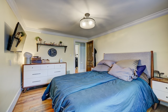 bedroom with light wood-style floors, crown molding, and baseboards