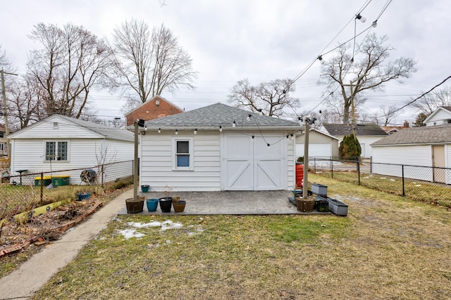 back of house with a garage, a fenced backyard, an outbuilding, and a yard