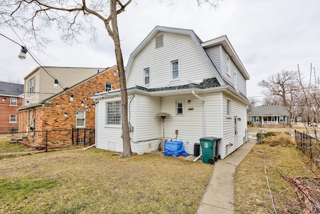 back of property with a shingled roof, a lawn, a fenced backyard, and a gambrel roof