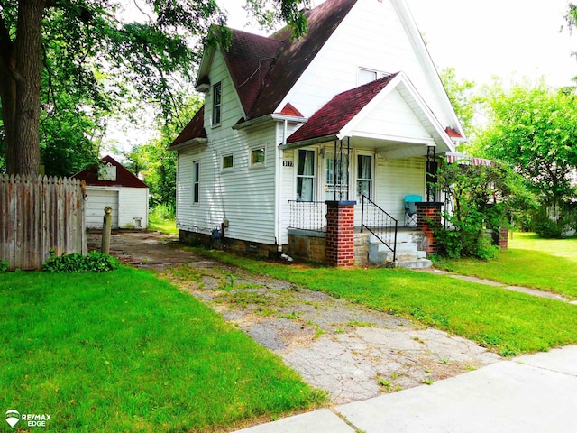 view of front of property featuring an outbuilding, a porch, a garage, and a front lawn