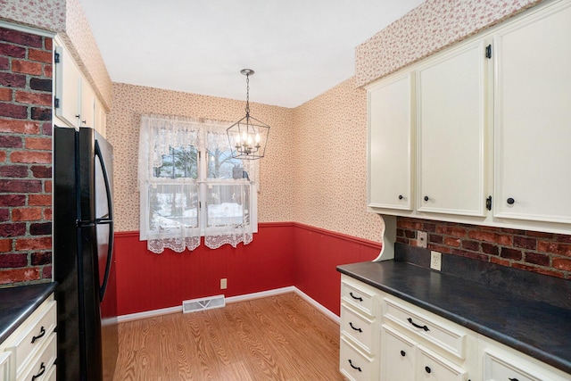 kitchen featuring black refrigerator, a chandelier, light hardwood / wood-style flooring, and pendant lighting