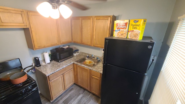 kitchen with black appliances, sink, light stone counters, ceiling fan, and dark wood-type flooring