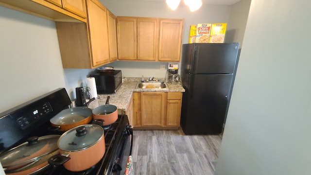 kitchen featuring sink, light hardwood / wood-style flooring, and black appliances