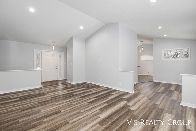 unfurnished living room featuring lofted ceiling, dark wood-style flooring, and baseboards
