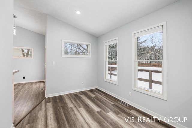 spare room featuring lofted ceiling, dark wood-style flooring, visible vents, and baseboards