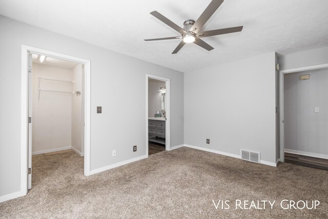 unfurnished bedroom with connected bathroom, baseboards, a closet, carpet, and a walk in closet