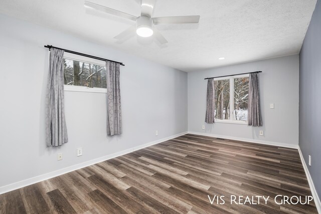 spare room with dark wood-type flooring, ceiling fan, a textured ceiling, and baseboards