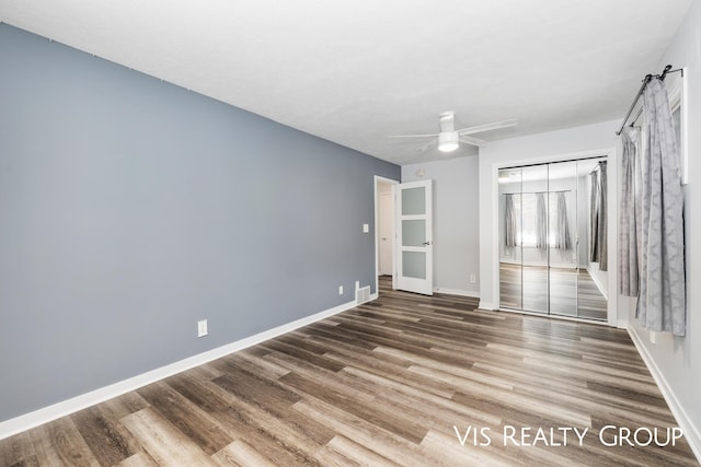 unfurnished bedroom featuring visible vents, ceiling fan, baseboards, and wood finished floors