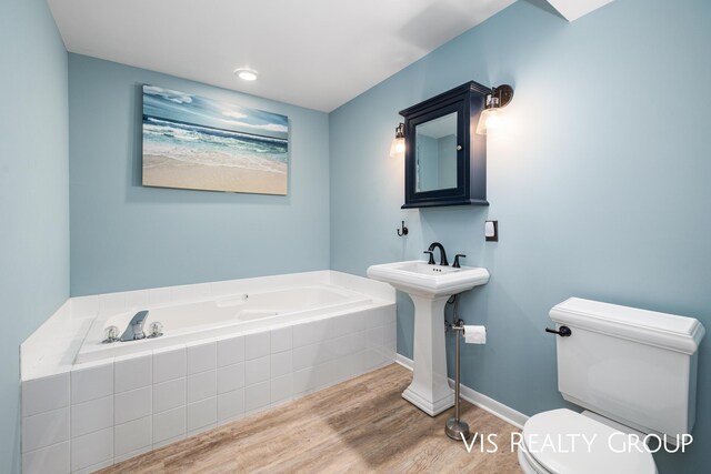 full bathroom with baseboards, a garden tub, toilet, and wood finished floors