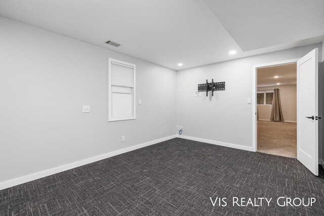 unfurnished room with dark colored carpet, visible vents, baseboards, and recessed lighting