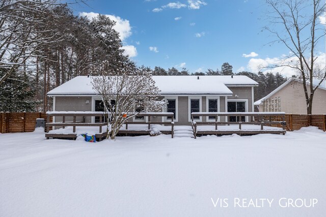 snow covered rear of property with fence and a deck