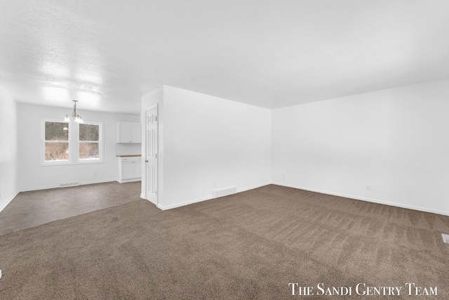 carpeted empty room with an inviting chandelier