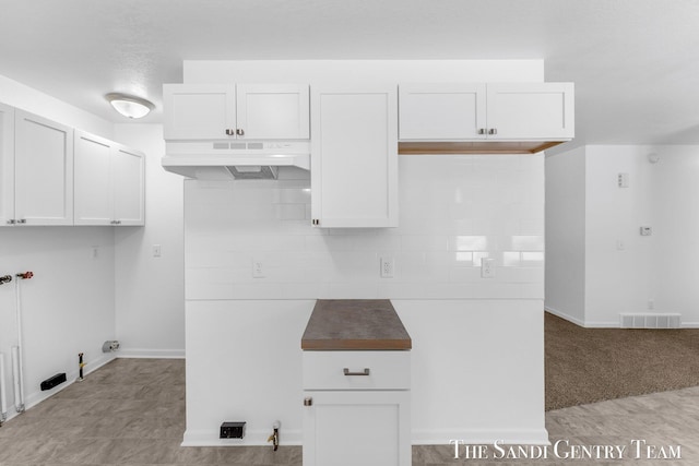 kitchen with white cabinetry, light carpet, and backsplash