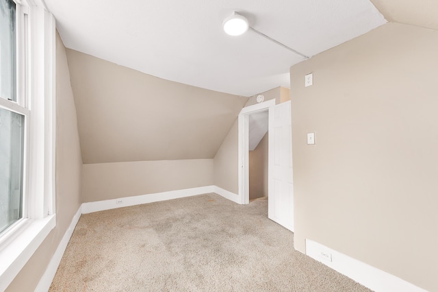 bonus room featuring vaulted ceiling and light carpet