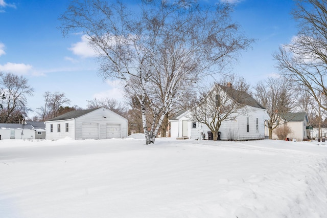 snowy yard featuring an outbuilding and a garage