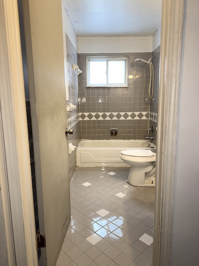 bathroom with tiled shower / bath combo, tile patterned floors, and toilet