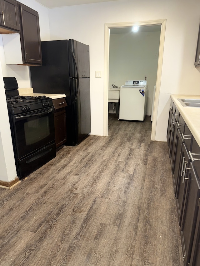 kitchen with dark brown cabinetry, black range with gas cooktop, sink, wood-type flooring, and washer / clothes dryer