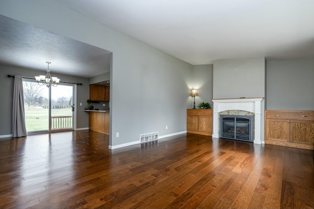 unfurnished living room featuring a tiled fireplace, dark hardwood / wood-style floors, and an inviting chandelier