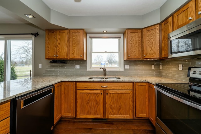 kitchen featuring appliances with stainless steel finishes, tasteful backsplash, sink, light stone countertops, and dark wood-type flooring