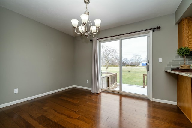 unfurnished dining area with dark hardwood / wood-style flooring and an inviting chandelier