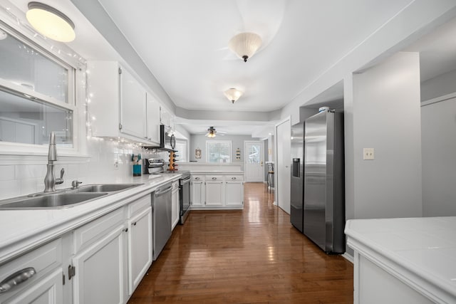 kitchen with tasteful backsplash, sink, white cabinets, stainless steel appliances, and dark wood-type flooring