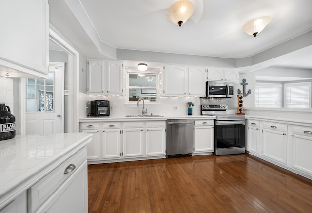 kitchen with white cabinetry, appliances with stainless steel finishes, sink, and dark wood-type flooring