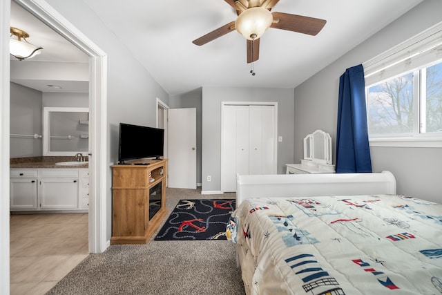 bedroom featuring sink, ensuite bath, light carpet, a closet, and ceiling fan