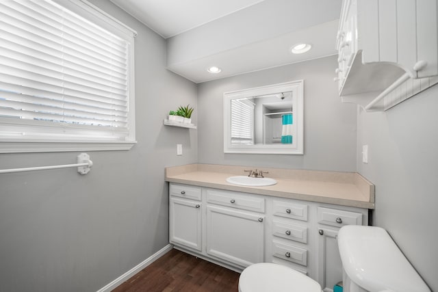 bathroom with hardwood / wood-style flooring, a healthy amount of sunlight, vanity, and toilet