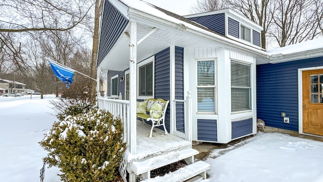 snow covered property with covered porch