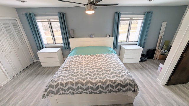 bedroom featuring a ceiling fan, a closet, multiple windows, and light wood finished floors